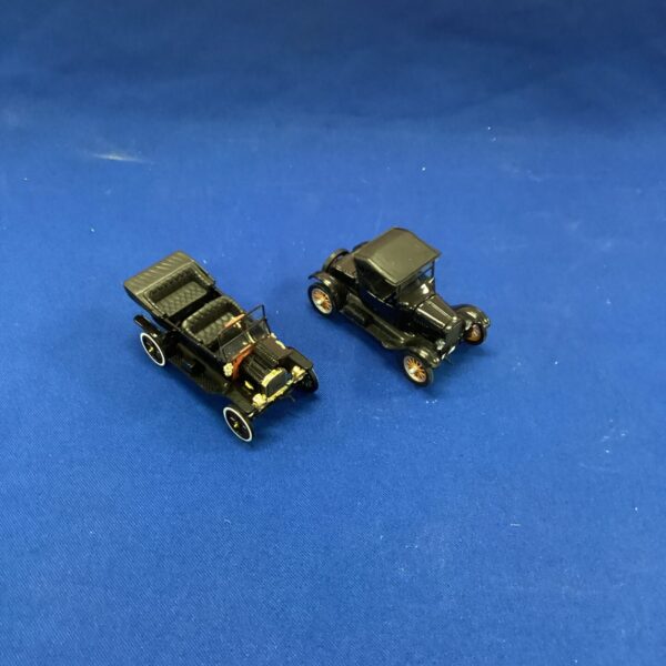Pair of vintage Ford Model T model cars on a blue background.