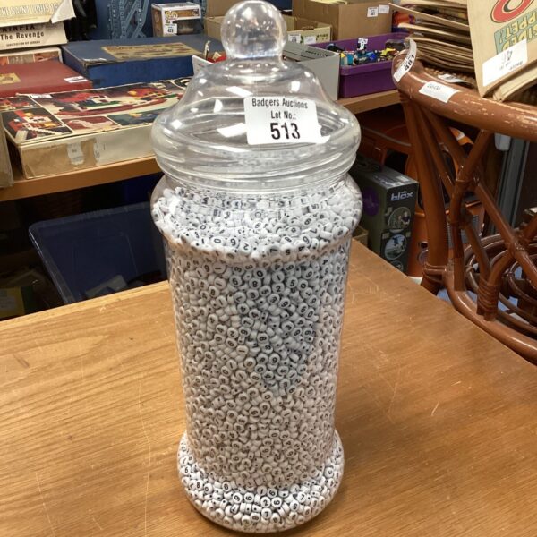Clear glass jar filled with numerous numbered plastic beads.