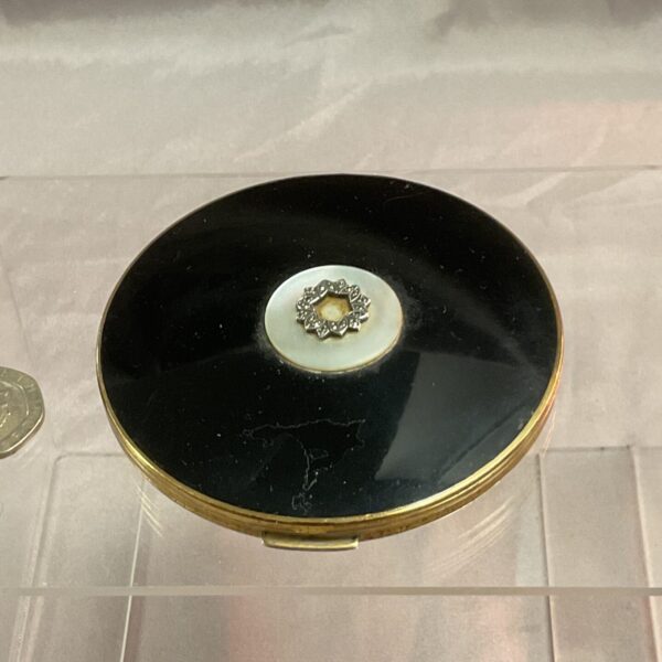 Angled view of vintage Stratton compact with black enamel.