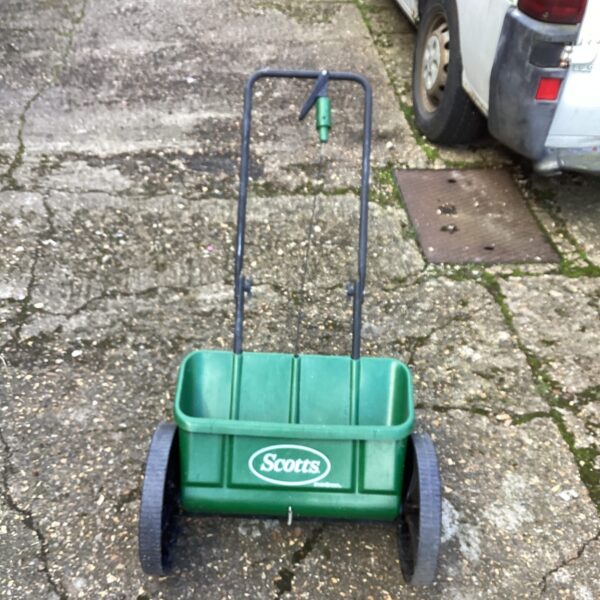 Vintage Scott Lawn Feeder in green plastic with metal wheels.