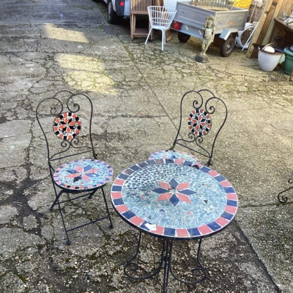 Colourful mosaic garden table and two chairs in a garden setting.