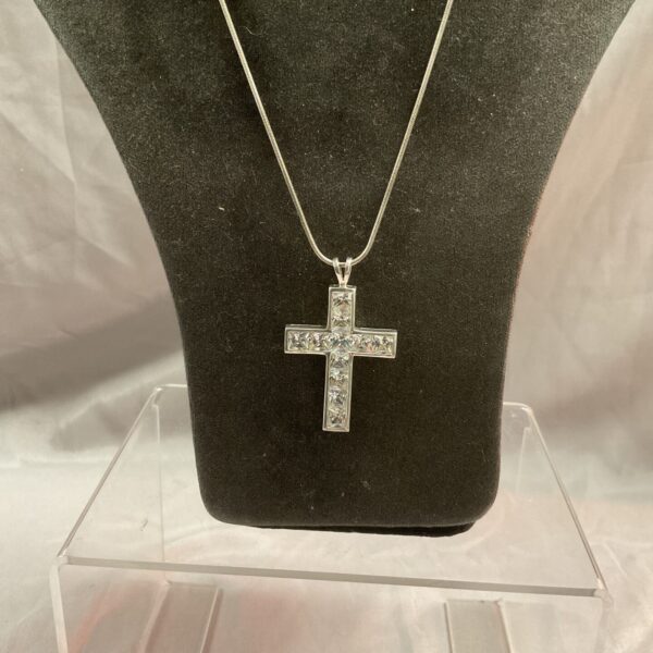 Silver cross necklace with white stone pendant on snakelink chain.