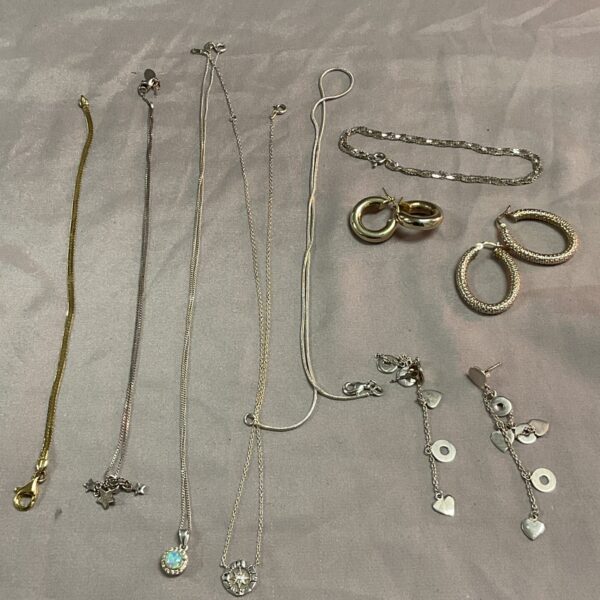 Collection of 925 silver necklaces and earrings on a neutral background.