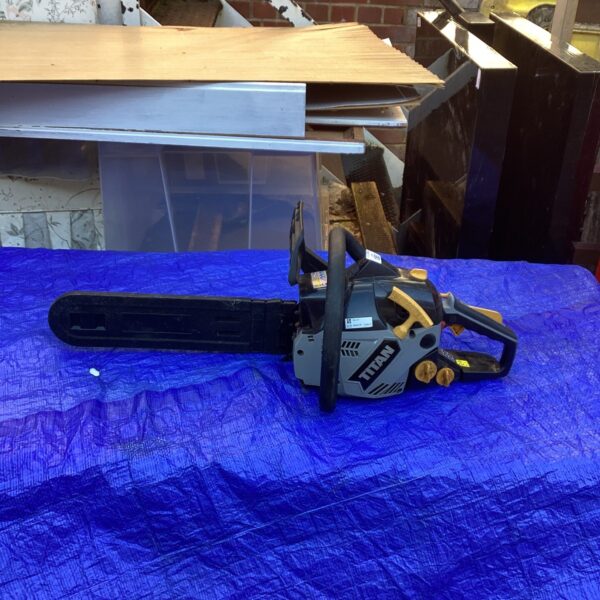 Side view of a used Titan petrol chainsaw for garden work.