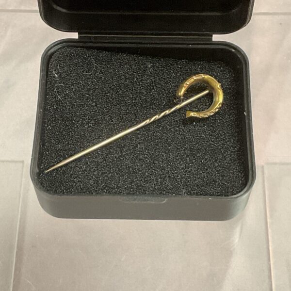 Vintage 15ct gold horseshoe stick pin on display.