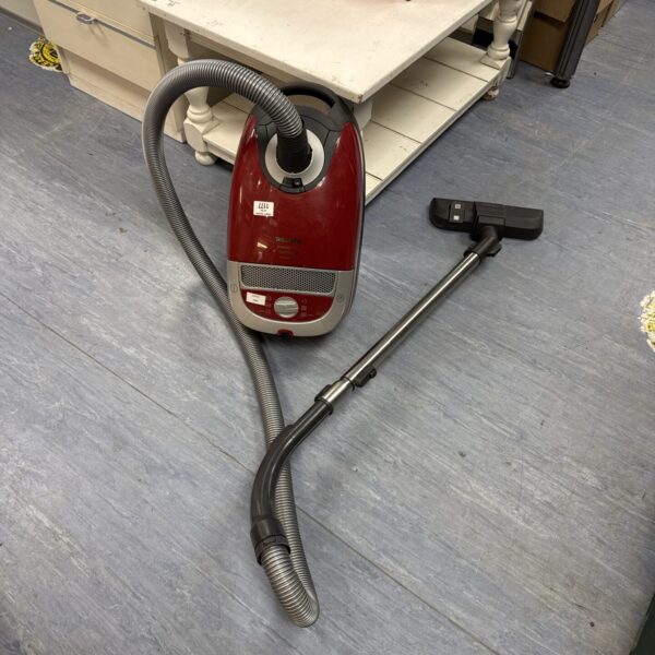 Red Miele Complete C2 cylinder vacuum cleaner with hose attached.