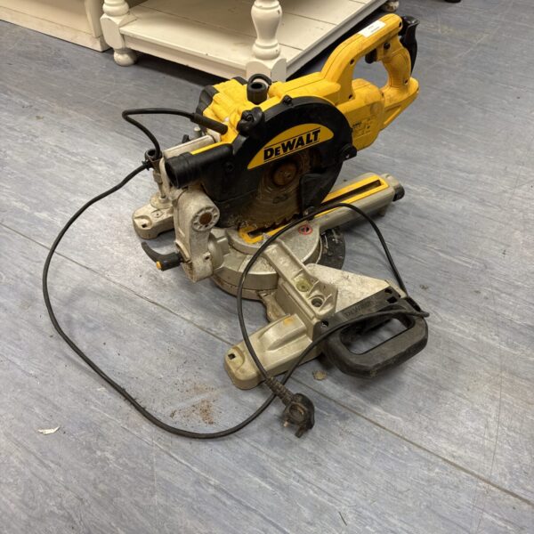 Front view of a used Dewalt chop saw on a grey floor.
