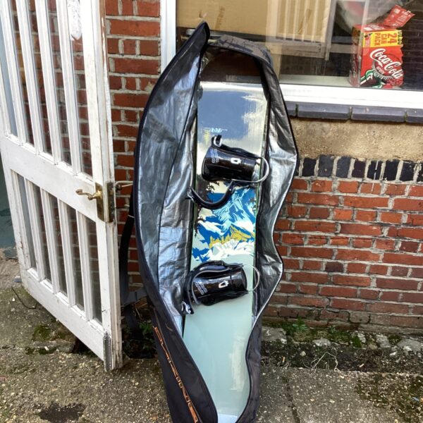 Black snowboard carry case leaning against a brick wall.