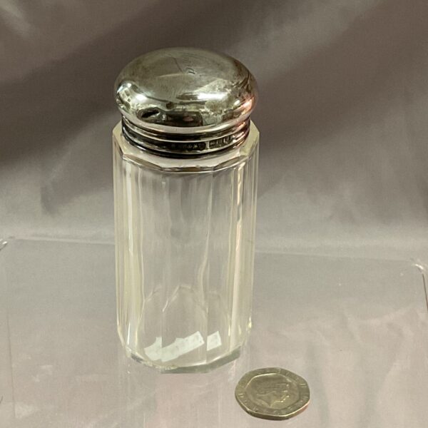 Antique silver lid hairpin pot on a glass surface.