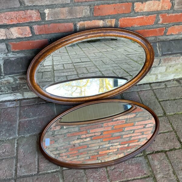Pair of vintage mid-century oval mirrors with oak frames.