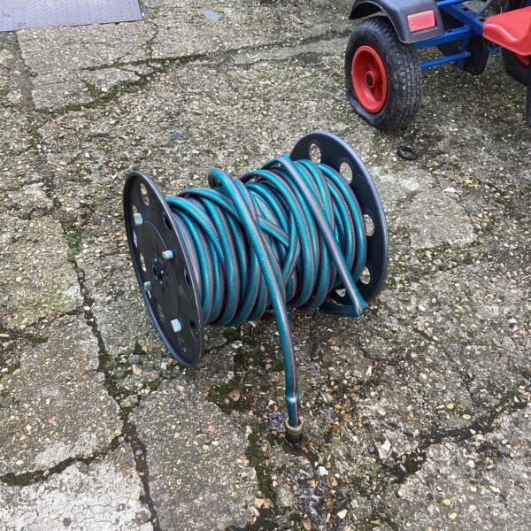 Close-up of a plastic garden hose reel with a green hose.