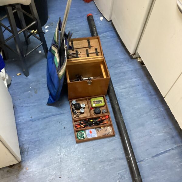 Vintage fishing tackle box with rod and assorted angling gear.
