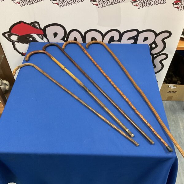 Bundle of vintage walking canes with wooden shafts and handles.