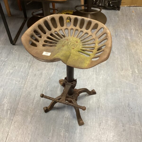 Vintage tractor seat stool with adjustable base and weathered finish.