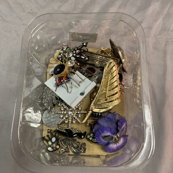 Vintage costume jewellery brooches displayed on a tray, colourful pin collection.