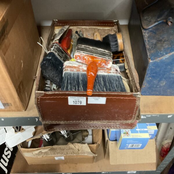 Mixed lot of used paint brushes in a cardboard box.