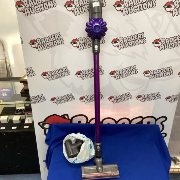 Dyson cordless vacuum cleaner with charger and accessories on display.