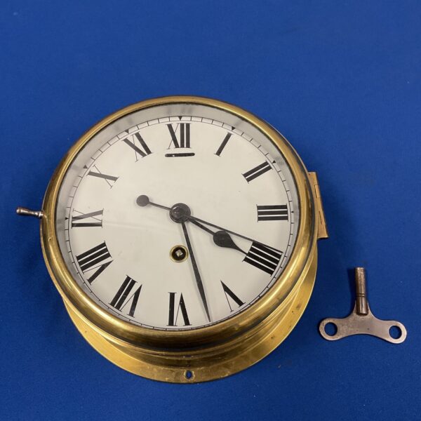 Vintage brass ships clock with Roman numerals and winding key.