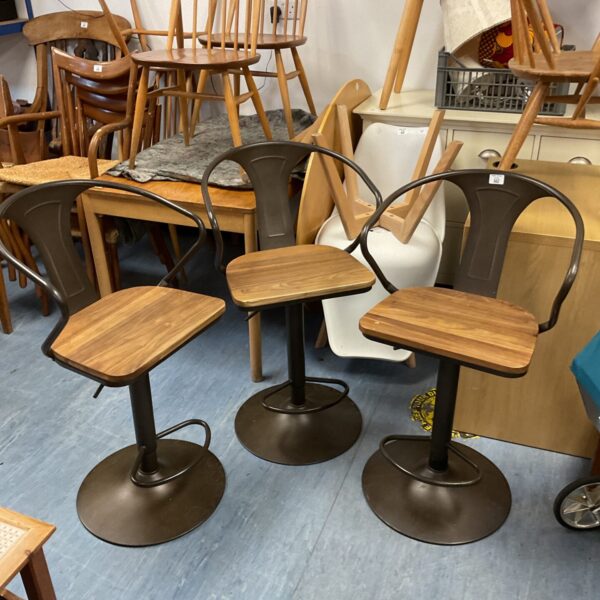 Three rustic wooden swivel bar stools with chrome bases.