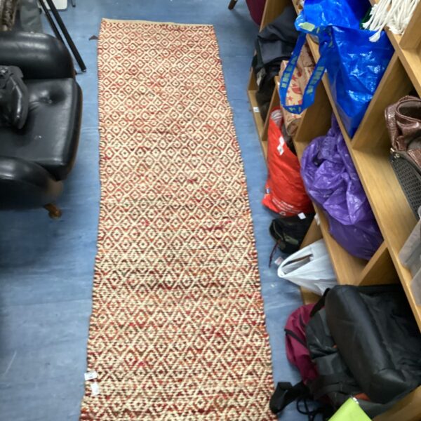 Vibrant woven rug with cream, orange, and red geometric pattern.