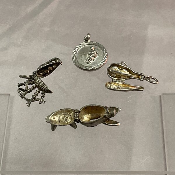 Antique silver charm lot featuring bagpipes, piggy bank, and violin.