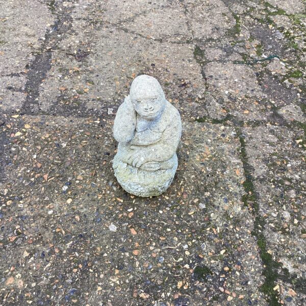 Concrete garden gorilla ornament seated in a garden setting.
