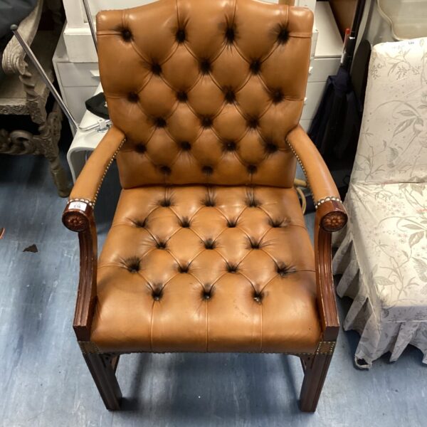 Vintage brown leather armchair with button-tufted back.