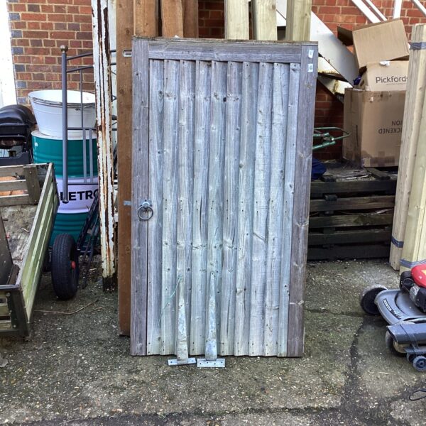 Weathered rustic wooden garden gate with metal hinges.