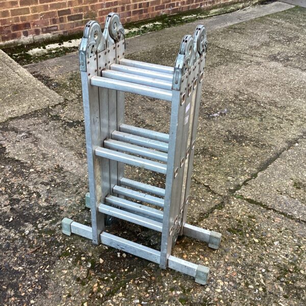 Silver aluminium multi-purpose ladder leaning against a wall.