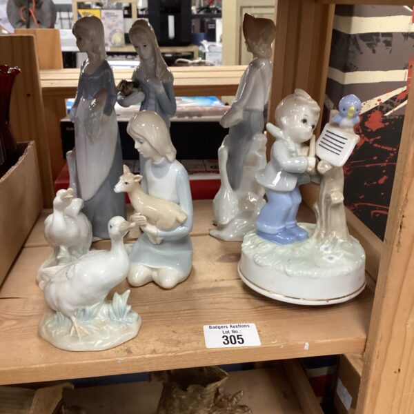 Vintage porcelain figurines of a shepherdess, boy, and lambs.