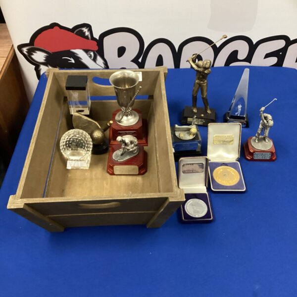Collection of vintage golfing trophies in a wooden tub.