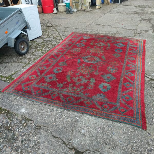 Large red rug with intricate floral pattern, vintage style.