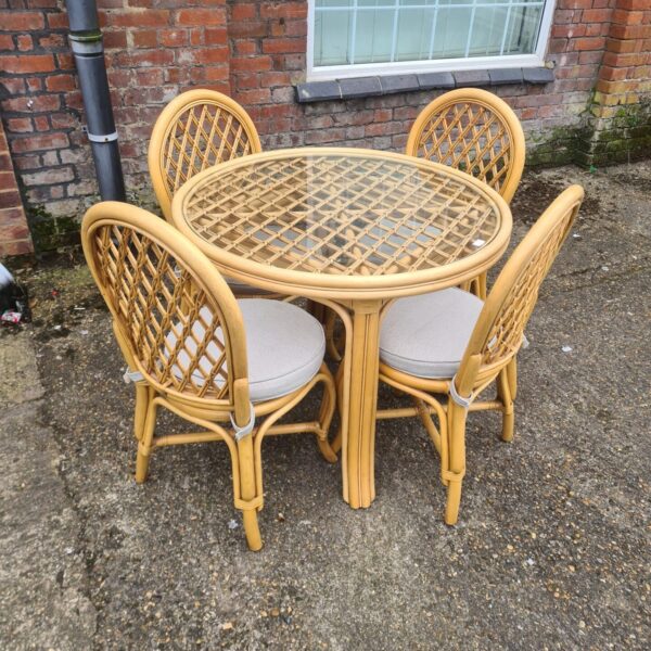 Vintage bamboo conservatory table and chairs set in a garden.