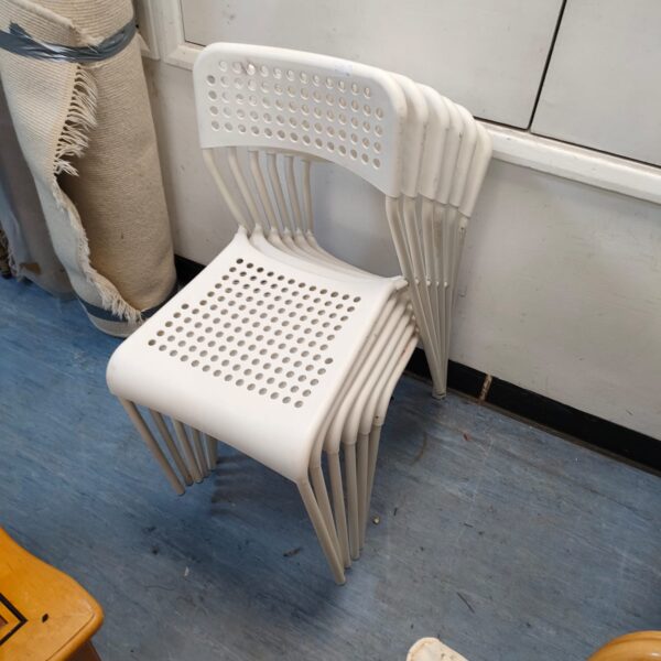 Lot of six plastic garden chairs stacked together.