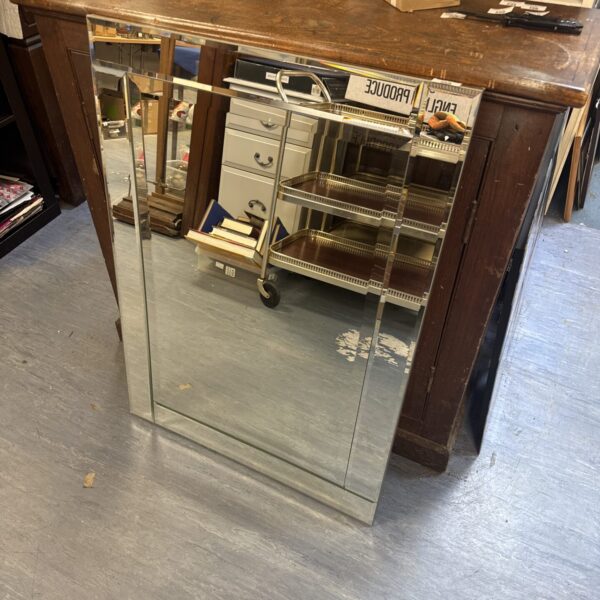 Antique bevelled glass mirror with dark wood frame.