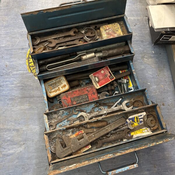 Open vintage cantilever toolbox filled with antique tools.
