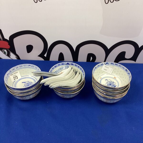 Vintage Chinese porcelain soup dishes with spoons on display.