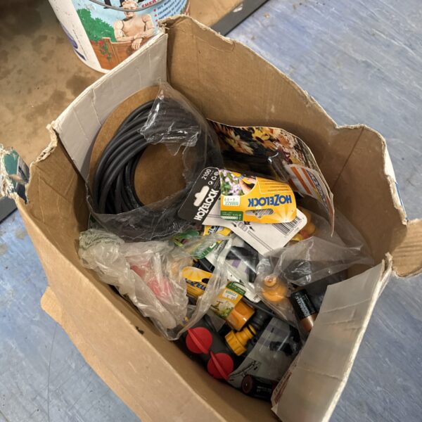 Assorted garden hose fittings and parts in a cardboard box.