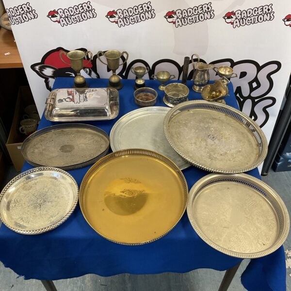 Vintage silver plate serving trays and trophies collection on display.
