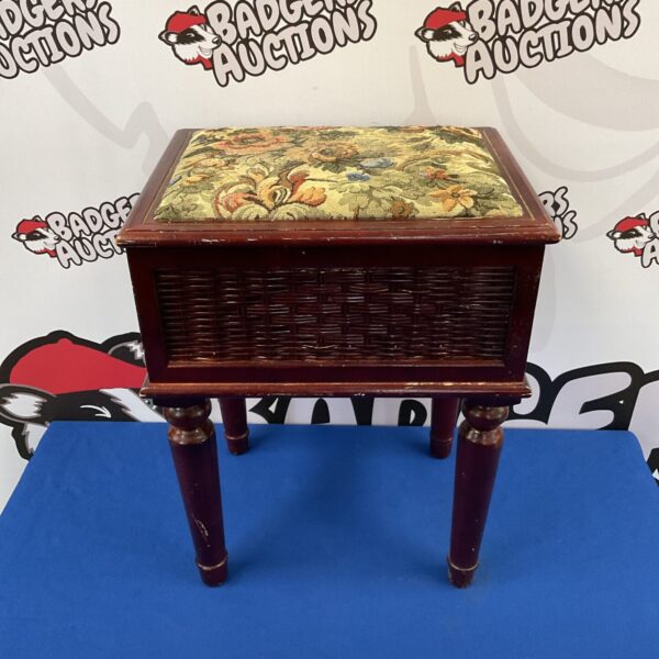 Antique sewing table with a floral embroidered top and turned legs.