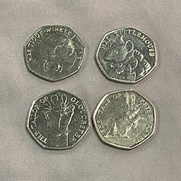 Group of four Beatrix Potter 50p coins, including Peter Rabbit.