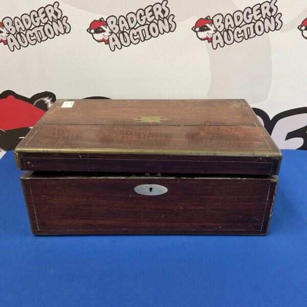 Antique Victorian writing slope with brass keyhole and wood grain.
