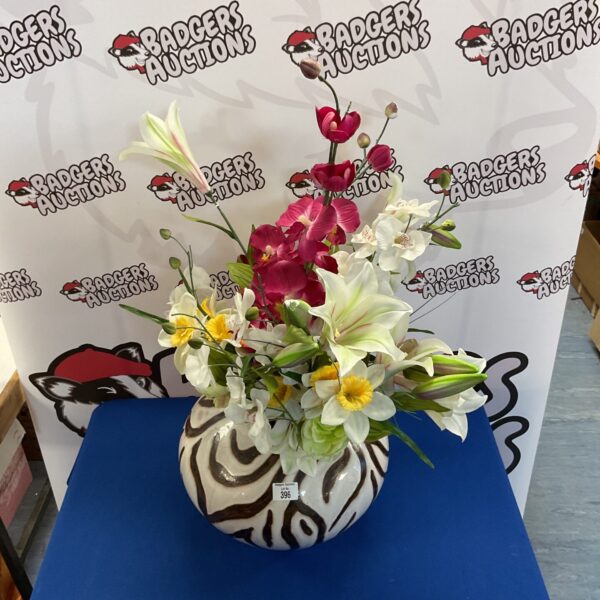 Vibrant faux flowers in a bold zebra print vase.