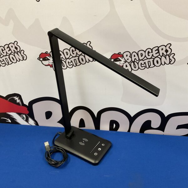 Modern USB LED desk lamp with phone charging port on a dark surface.