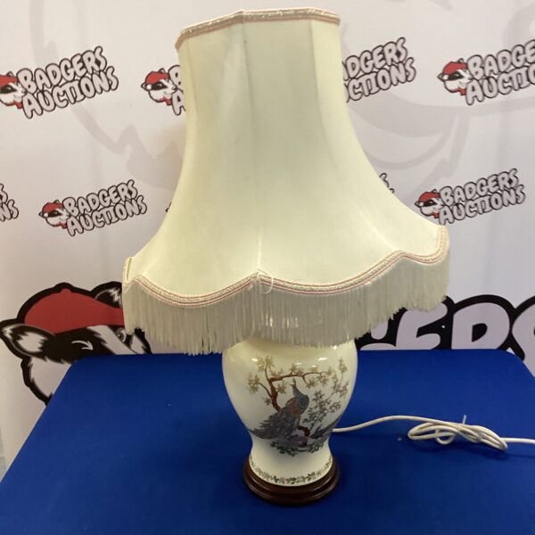 Vintage cream table lamp with peacock design and lampshade.