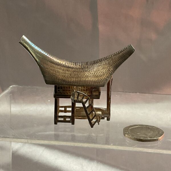 Detailed silver Tongkonan model, showcasing Indonesian architecture.