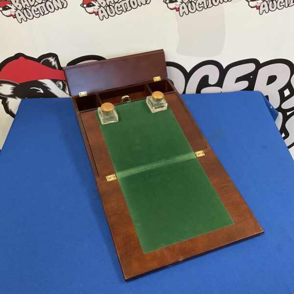 Open antique mahogany writing slope with inkwells displayed.