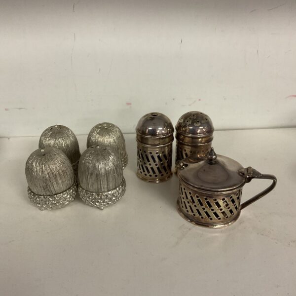 Antique silver plate salt, pepper, and mustard set on a white surface.