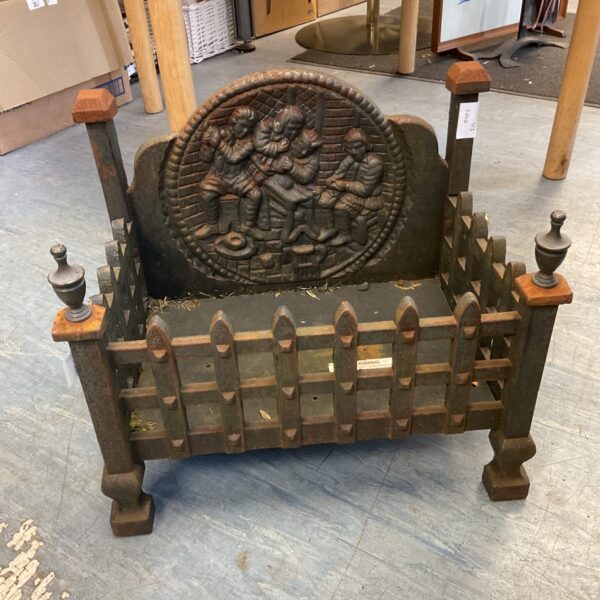 Antique cast iron fireplace insert with tavern scene detail.