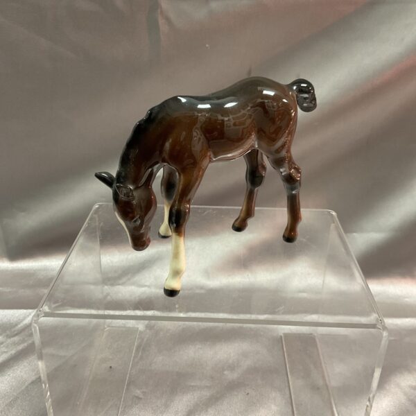 Vintage Beswick brown foal figurine grazing in a field.